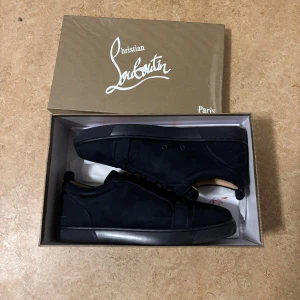 Mörkblå Christian Louboutin - Säljer ett par mörkblå sneakers från Christian Louboutin med snygg signatur på hälen och röd sula med logotyp. Skorna har rund tå, platt sula och är tillverkade i mocka med snörning. Perfekt för dig som gillar exklusiv och stilren design. kvitto finns!