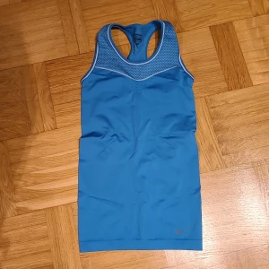 Blå Nike Pro träningstopp XS - Nike Pro linne i blått med meshdetaljer upptill och vita kantband. Modellen är ärmlös med brottarrygg och tillverkad i Dri-FIT-material som andas. Perfekt för träning och sportiga aktiviteter.