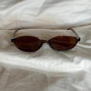 Bruna smala solglasögon - ÄLSKAR dessa bruna solglasögon med smal, oval form och transparent brun plastbåge. Glasen är också bruna och ger en cool retrovibe. Perfekt accessoar för att lyfta varje outfit!!💕💕