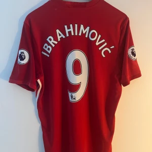 Manchester United Ibrahimovic tröja L - Röd Manchester United matchtröja med Ibrahimovic och nummer 9 på ryggen. Adidas Climacool-material, Premier League-patch på ärmarna och klassiska klubbmärket samt Chevrolet-logga på bröstet. Snygga vita detaljer och tryck, perfekt för fans av Zlatan.