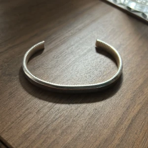 Silverfärgat armband från Skultuna - Stilrent armband i silver från Skultuna med graverad logga och räfflad insida. Öppen design som gör det enkelt att ta på och av. Perfekt accessoar för dig som gillar minimalistisk och tidlös stil.