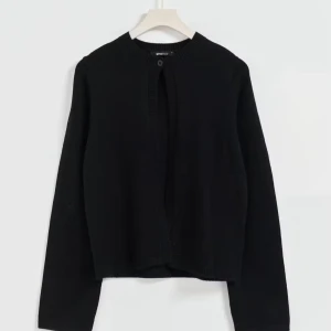 Svart stickad kofta  - En svart, enkel och stilren stickad kofta från Gina Tricot. Koftan har rund halsringning, lång ärm och en knapp upptill. Perfekt att slänga över en topp för en chill look. Materialet är mjukt och skönt stickat.