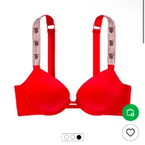 Röd push-up topp från Victoria's Secret - Snygg röd push-up topp från Victoria's Secret med breda axelband dekorerade med VS-logga och glittriga detaljer. Axelbanden är justerbara och ger en sportig men ändå glam känsla. Perfekt för dig som vill sticka ut lite extra. Kostar 1200 nypris!! Storlek 75b passar större och mindre