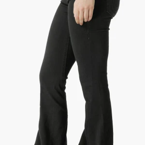 Svarta low flare true religion jeans - Snygga svarta jeans med bootcut-modell och klassisk femficksdesign. Jeansen har en figurnära passform upptill och utsvängda ben, vilket ger en retrovibe. Perfekta att matcha med sneakers eller boots för en cool look. Endast testade en gång, helt nya med prislappen kvar. Säljer för att de var för korta på mig som är 163 cm. De är i storlek W23/L32. 