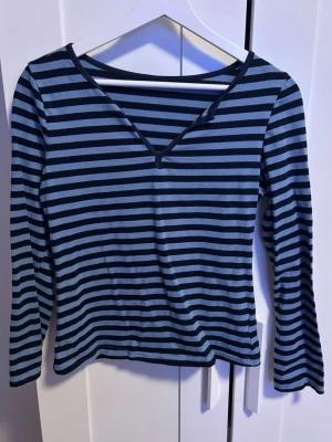 Randig långärmad topp blå/svart - Säljer en långärmad topp i storlek S med marinblå och svarta horisontella ränder. Toppen har v-ringad hals. 