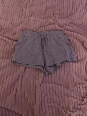 Grå mjuka shorts med resårmidja - Supersköna grå shorts med elastisk midja och avslappnad passform. Tillverkade i ett mjukt och tunt bomullsliknande material, perfekta för varma dagar eller att chilla hemma. Har fickor på sidorna för extra bekvämlighet.