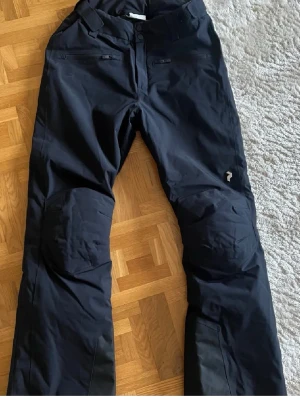 Peak Performance överdragsbyxor – stl 38 – sparsamt använda - Säljer ett par stilrena och funktionella överdragsbyxor från Peak Performance i storlek 38. Byxorna är sparsamt använda och i mycket fint skick, inga kända skador eller slitage.  📍 Märke: Peak Performance 📏 Storlek: 38 🎨 Färg: Svart ✨ Skick: Mycket bra  Hör av dig vid frågor!