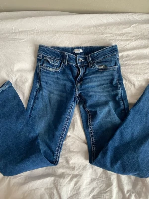 Blå jeans från Gina Tricot, storlek 170 - Säljer ett par klassiska blå jeans från Gina Tricot i storlek 170. Jeansen har fem fickor, snygga kontrastsömmar och knappdetalj på bakfickan. Modellen är rak med normal passform och tillverkad i mjukt denimtyg som är skönt att bära hela dagen. 💙