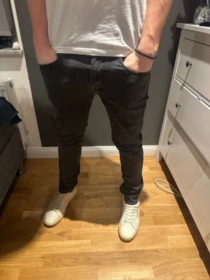 Mörkgrå skinny jeans Sharp 31/32 - Säljer ett par svarta jeans från tiger of Sweden i modellen Progr. Darkened. Jeansen har klassisk femficksdesign, låg midja och smal passform hela vägen ner. Som ni ser på bild 4 är Jensen lite smutsiga med vit målar färg. Men inget som man märker när man har de på🔥