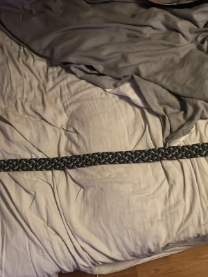 Flätat bälte från ONEWear Sweden - Säljer ett snyggt flätat bälte från ONEWear Sweden i svart, grått och vitt. Bältet har ett klassiskt metallspänne och detaljer i svart skinn. Perfekt accessoar för att lyfta din outfit.