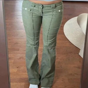 Gröna bootcut byxor med fickor - Snygga gröna byxor med bootcut-modell och låg midja. Byxorna har fram- och bakfickor samt markerade sömmar längs benen. Perfekta för dig som gillar en retro vibe och vill ha något som sticker ut lite extra.