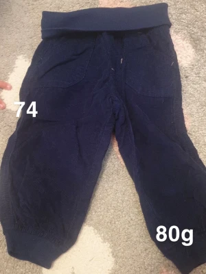 Mörkblå manchesterbyxor barn - Mörkblå manchesterbyxor för barn med bred mudd i midjan och vid benslut. Byxorna har två stora fickor framtill och är gjorda i mjukt manchestertyg som är skönt mot huden. Perfekta för lek och vardag.🌸 Fint använt skick. Storlek 74