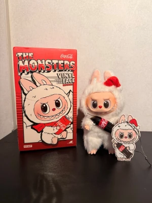 Popmart The Monsters Labubu x Coca-Cola – Surprise Shake - Säljer en Labubu Surprise Shake från Pop Mart’s Coca-Cola-serie The Monsters. Figuren är klädd i den vita, fluffiga dräkten och håller en Coca-Cola-flaska. En rolig och fin figur som passar både samlare och den som vill ha den som dekoration eller hängande accessoar.  Kort om figuren: 	•	Original från Pop Mart 	•	Del av Coca-Cola samarbetet 	•	Vinylfigur med mjuka detaljer 	•	Har nyckelring/strap 	•	I fint skick  Har blivit över i samlingen och säljs därf