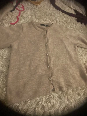 Beige kofta med pärlknappar från 157 - Mysig kortärmad beige kofta från 157 i storlek S. Sälj pågrund av att den är för liten💕saknar dock en knapp längs ner 