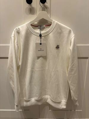 Moncler tröja - Säljer en stilren vit sweatshirt från Moncler i nyskick, aldrig kommit till användning:)