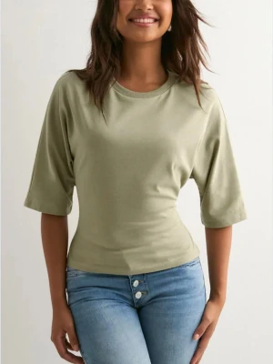 Ljusgrön croppad topp med knyt - Snygg ljusgrön croppad topp i bomull med halvlånga ärmar och rund halsringning. Toppen har en öppen rygg med breda band som knyts i en rosett bak, vilket ger en cool och trendig look. Perfekt att matcha med jeans eller kjol. Nästan helt ny, utan prislapp! Endast använd en gång