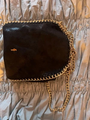 Svart handväska med guldkedja - Skit snygg handväska, säljer då jag inte använder den längre.