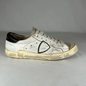 Philippe Model vita sneakers med svart detalj - Säljer ett par Philippe Model sneakers i vitt skinn med grå mockadetaljer på tån och svart häl. Klassisk logga på sidan och breda vita snören. Snygg vintage-look med kontrasterande sula och coola detaljer. Perfekta för dig som gillar streetstyle. Storlek 40 men passar även för 41 !!!