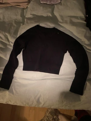 Svart croppad långärmad topp SOC - Säljer en svart croppad långärmad topp från SOC. Toppen är ribbad och har en tight passform som sitter snyggt på kroppen. Tillverkad i ett stretchigt material med 96% polyamid och 4% elastan. Perfekt till träning.