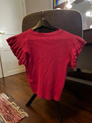 Rosa topp med volangärmar Gina Tricot - Säljer en rosa topp från Gina Tricot i storlek 158/164. Toppen har korta volangärmar och är ribbad i materialet vilket ger en snygg struktur. Perfekt för dig som gillar färg och vill ha något som sticker ut lite extra.