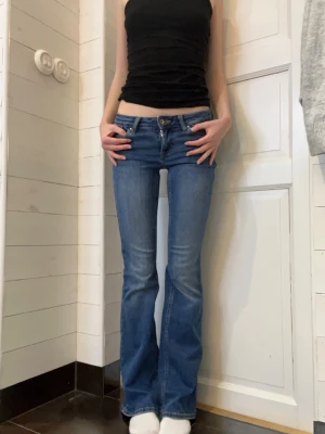 Blå bootcut jeans från ONLY - Säljer ett par blå bootcut jeans från ONLY med låg midja. Jeansen har klassisk femficksdesign, gul kontrastsöm och dragkedja med knapp. Materialet är mjukt denim med lite stretch. Lite slitna längst ner på benen. Storlek XS/32.