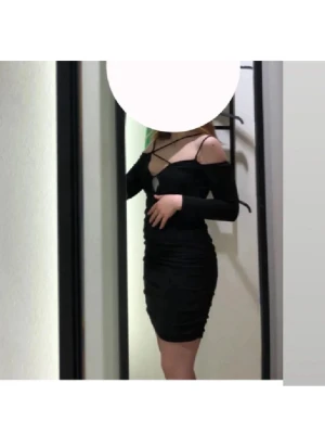 Svart offshoulder kort klänning -  en svart klänning med offshoulder och långa ärmar. Klänningen har en snygg cut-out framtill och tunna axelband som korsas över bröstet. Mycket stretch i så passar S-L tror jag. Använd en gång så typ ny💕