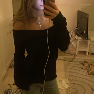 Svart offshoulder stickad tröja - Säljer en svart stickad tröja med offshoulder-design och långa ärmar. Tröjan har en loose passform och är perfekt för dig som gillar en avslappnad och trendig stil. Supermjuk och skön att bära, passar perfekt till jeans eller kjol.