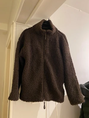 Brun teddyjacka från Gina Tricot  - Mysig brun teddyjacka från Gina Tricot i storlek XS men är oversize så den passar upp till L eller XL. Jackan har hög krage, dragkedja framtill  och är gjord i fluffigt teddy-material. Perfekt för kalla dagar 