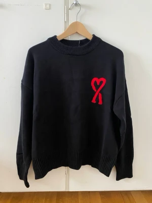 Ami Paris Stickad Tröja – Svart - Storlek: M Skick: Ny & oanvänd  Svart stickad Ami Paris-tröja med röd broderad Ami de Cœur-logga. Mjuk stickning, ribbade avslut och elegant passform. En mer uppklädd modell som funkar både casual och dressat. Pris kan diskuteras om du är intresserad 