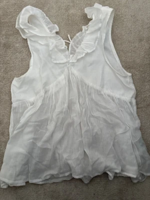 Vit blus med volang från Gina Tricot - Säljer en söt vit blus från Gina Tricot i storlek 170. 