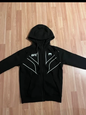 UFC hoodie - Säljer nu en UFC hoodie med dragkedja i storlek XS, kan nog passa S också beroende på hur du vill den sitter, den är i väldigt bra skick skulle säga 9/10. Perfekt för vardagen eller inför träning (pris kan diskuteras lite vid snabb affär)