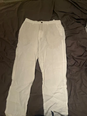 Vita linnebyxor från Zara, storlek M - Säljer ett par fräscha vita linnebyxor från Zara i storlek M. Byxorna har rak passform, sidofickor och knappstängning i midjan. Perfekta för varma dagar och har en clean look som är enkel att matcha med olika stilar.