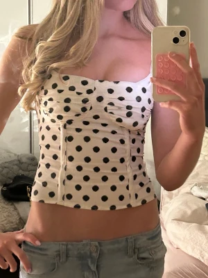 Prickig korsett topp med snörning - Snygg vit korsett topp med svarta prickar och justerbara axelband, snörning i bak💓💓 storlek xs men passar s-m då den knyts🥰