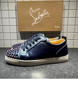 Mörkblå sneakers från Christian Louboutin - Tja, just nu så säljer jag mina Snygga mörkblå sneakers från Christian Louboutin. skorna är väldigt fint skick och endast testade ute en gång. allt original kommer med med boxen är till en annan sko. Har du några frågor så är det bara att ställa dem och jag tar alltid byten om du bor i Stockholm. skorna är självklart äkta. Mvh Oscar