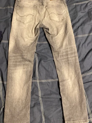 Grå slim jeans Jack & Jones Super Stretch - Slim fit jeans från Jack & Jones i en snygg grå tvätt med Super Stretch-material som ger extra bekväm känsla. Klassisk femficksmodell med raka ben och diskreta slitningar. Perfekta för dig som gillar en smalare passform och vill ha flexibla jeans.