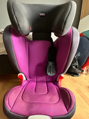 Bilbarnstol  - Bilderna visar en Britax Römer Kidfix XP SICT bilbarnstol i lila och svart. 