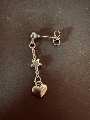 By prisförslag - 1 st Silverfärgad örhänge med stjärna och hjärta - snyggt örhänge i silverfärg med hängande kedja, dekorerad med en liten stjärna och ett hjärta. Perfekt för dig som gillar detaljer och vill ha något unikt till din stil. Passar till både vardagslooken och när du vill sticka ut lite extra.