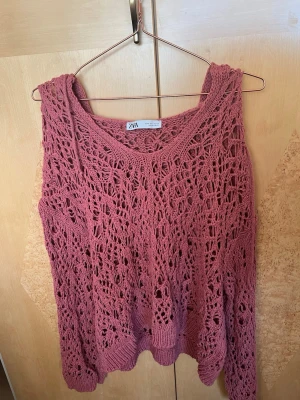stickad tröja från Zara med luva - Säljer en stickad tröja från Zara i storlek S. Tröjan har ett öppet, virkat mönster och en bred, rundad halsringning. Materialet är bomull och modellen är loose fit med långa ärmar. Perfekt för lager-på-lager och chill stil.