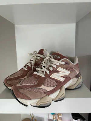New Balance 9060 sneakers rosa/beige - Säljer ett par New Balance 9060 sneakers i en snygg mix av rosa och beige toner. Skorna har chunky sula, meshpaneler och detaljer i mocka samt klassisk N-logga på sidan. Vita snören och cool retrovibe. Perfekta för dig som gillar streetstyle och bekväma skor. Använda fåtal gånger