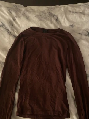 Brun långärmad topp Gina Tricot XXS - Säljer en mörkbrun långärmad topp från Gina Tricot i storlek XXS. Toppen har en liten slits vid ärmslutet. Och den är tight så skulle oxå passa st 152-xxs 