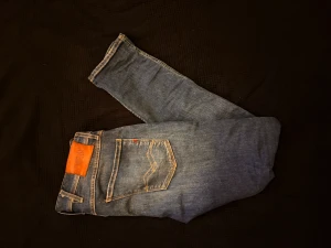 Replay Anbass jeans blå - Säljer ett par Replay Anbass jeans i klassisk blå tvätt med snygga slitningar och slim/straight  passform. Passar bra för dig runt 180 cm 