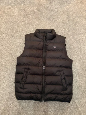 Gant Väst - Säljer en snygg svart gant väst till bra skick. Västen har två fickor och en dragkedja. Skicket är perfekt och det finns inga hål eller liknande. Köptes på Kidsbrandstore för ett tag sen för ungefär 1200 kr. Nästan aldrig användts 