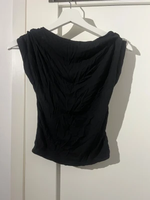 Öppen rygg topp -  Säljer en svart öppenrygg topp, använd några gånger men fortfarande i fint skick, tröjan sitter tajt och är i storlek xs