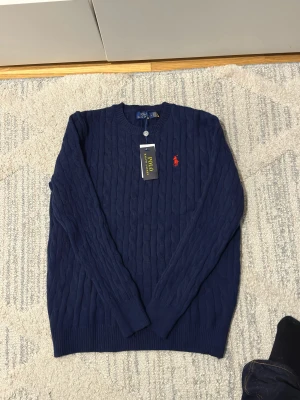 Mörk blå polo tröja - Helt ny Mörk blå polo tröja. Väldigt fin tröja som passar med flesta outfit och ör unik med röda logan