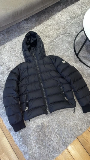 Svart Moncler dunjacka med huva - Moncler Dunjacka i svart | Äkta✅ Köpt från garmsmarket för 5200 förra året | Skick 9/10, inga fel endast cartoonen inuti jackan som är lite lös | Storlek 2 motsvarar S/M