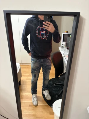 Mörkblå hoodie Från Tommy Hilfiger - Säljer en mörkblå hoodie från Tommy Hilfiger i storlek S. Den har broderad logga i rött, blått och vitt på bröstet, dragsko i huvan och en stor magficka. Väldigt skönt material, nypris 2000kr, jag är 181 72kg! BVSA
