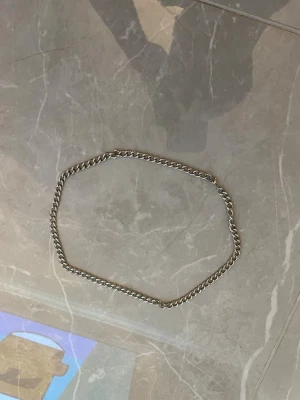 Två kedjehalsband i guld och silver - Säljer två stilrena halsband, ett i guldton och ett i silverton. Båda har klassisk kedjedesign, där det silvriga är lite grövre och det guldiga är tunnare och mer diskret. Perfekta för att lyfta din outfit med en enkel men snygg detalj.