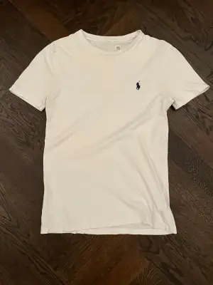 Snygg vit Ralph Lauren T-shirt i bra skick. Nacketiketten har bleknats ut i tvätten men annars är den i mycket fint skick. Storlek XS. Orginal pris 899kr