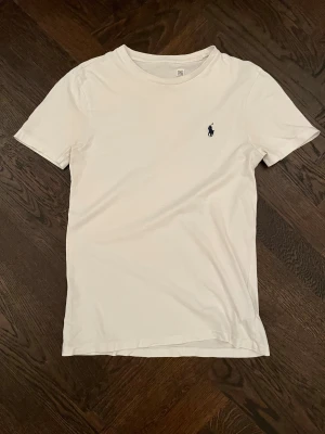 Vit Ralph lauren T-shirt - Snygg vit Ralph Lauren T-shirt i bra skick. Nacketiketten har bleknats ut i tvätten men annars är den i mycket fint skick. Storlek XS. Orginal pris 899kr