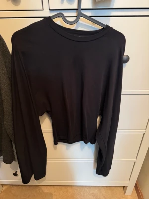 Svart långärmad tröja  - En enkel svart långärmad tröja från 157 i storlek XS. Tröjan har rund hals och är gjord i mjuk bomull, perfekt för chill dagar. Passformen är normal och den är helt utan mönster eller detaljer. Snygg att matcha med jeans eller joggers.